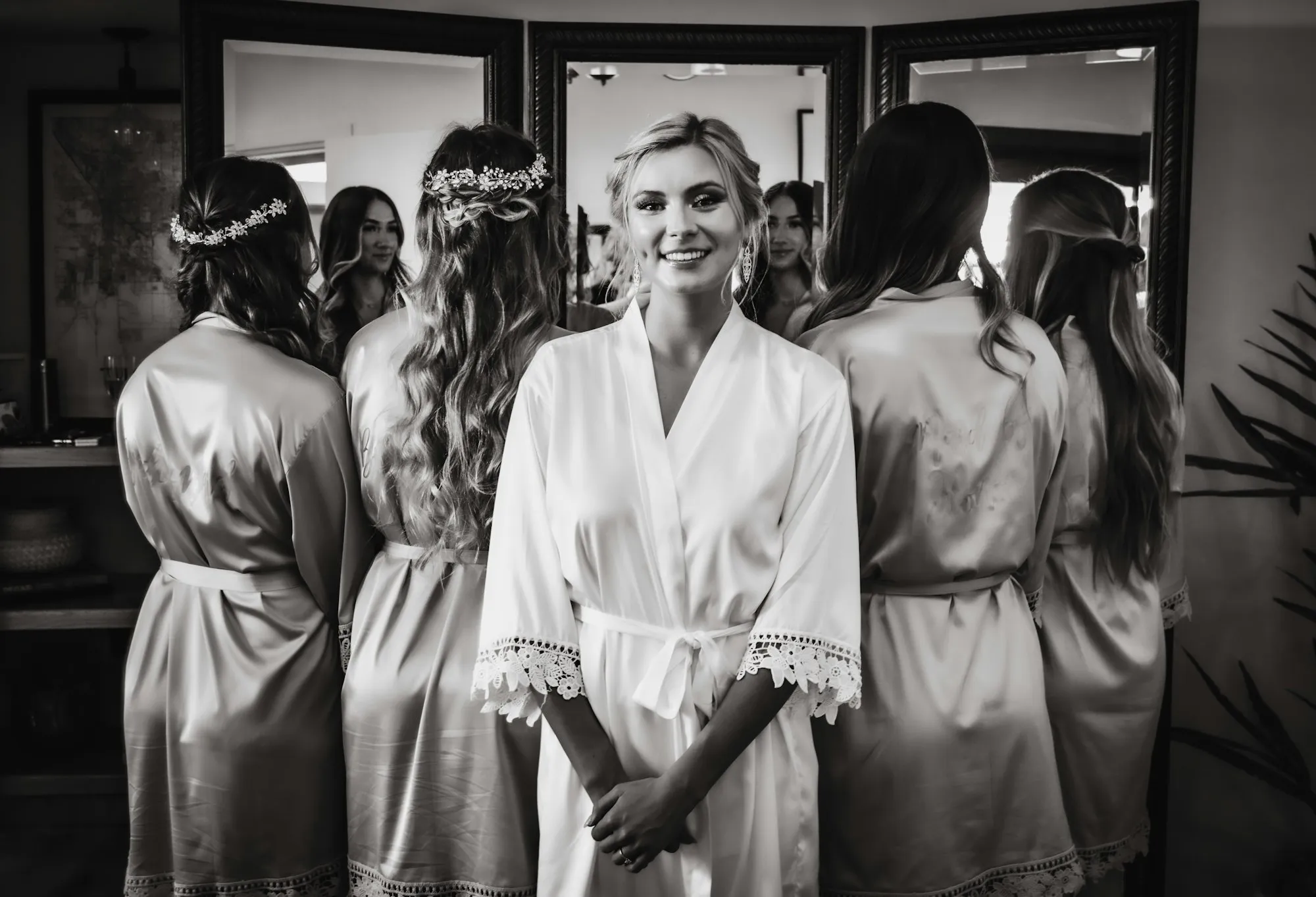 Black-and-white photo of a bride and bridesmaids in robes getting ready