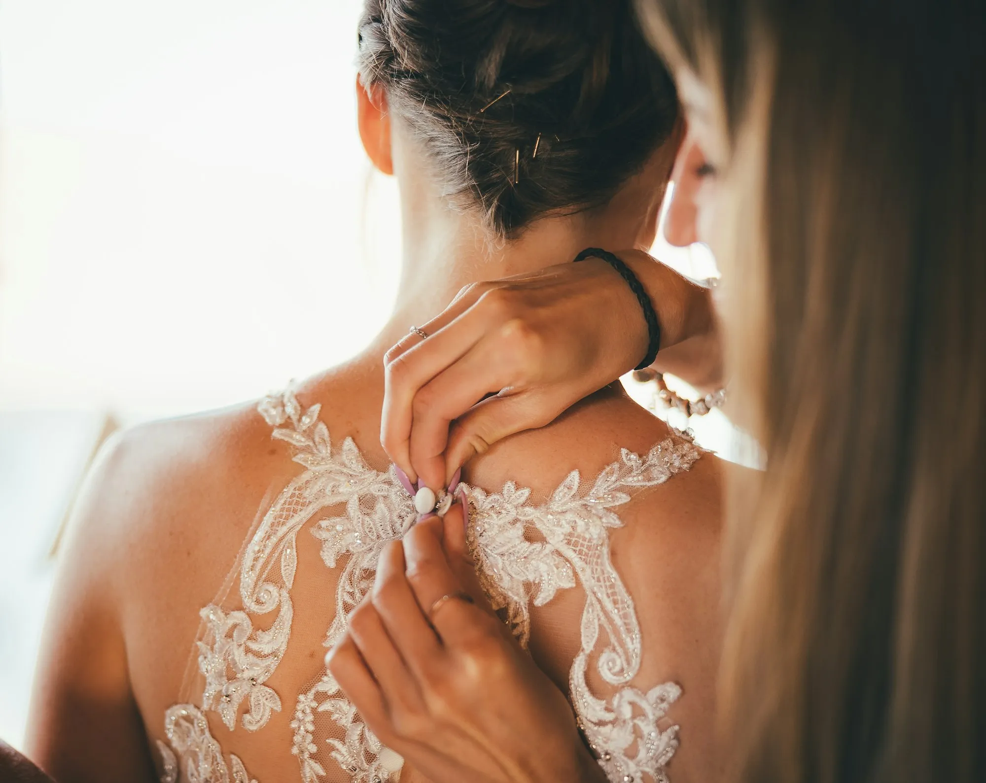 Close-up of a lace wedding dress being fastened
