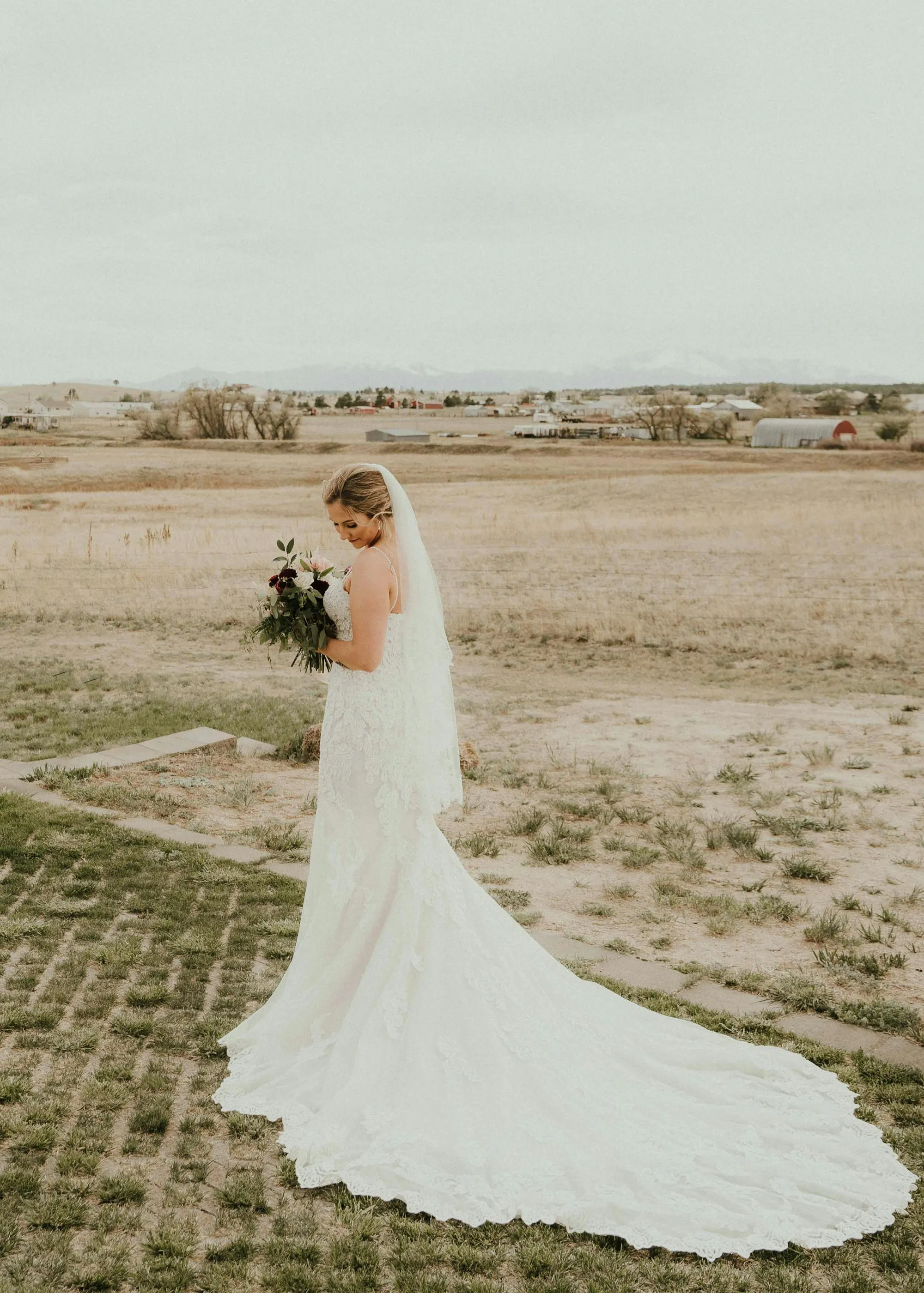 Bride walking through a dry grass field under a wide Colorado sky