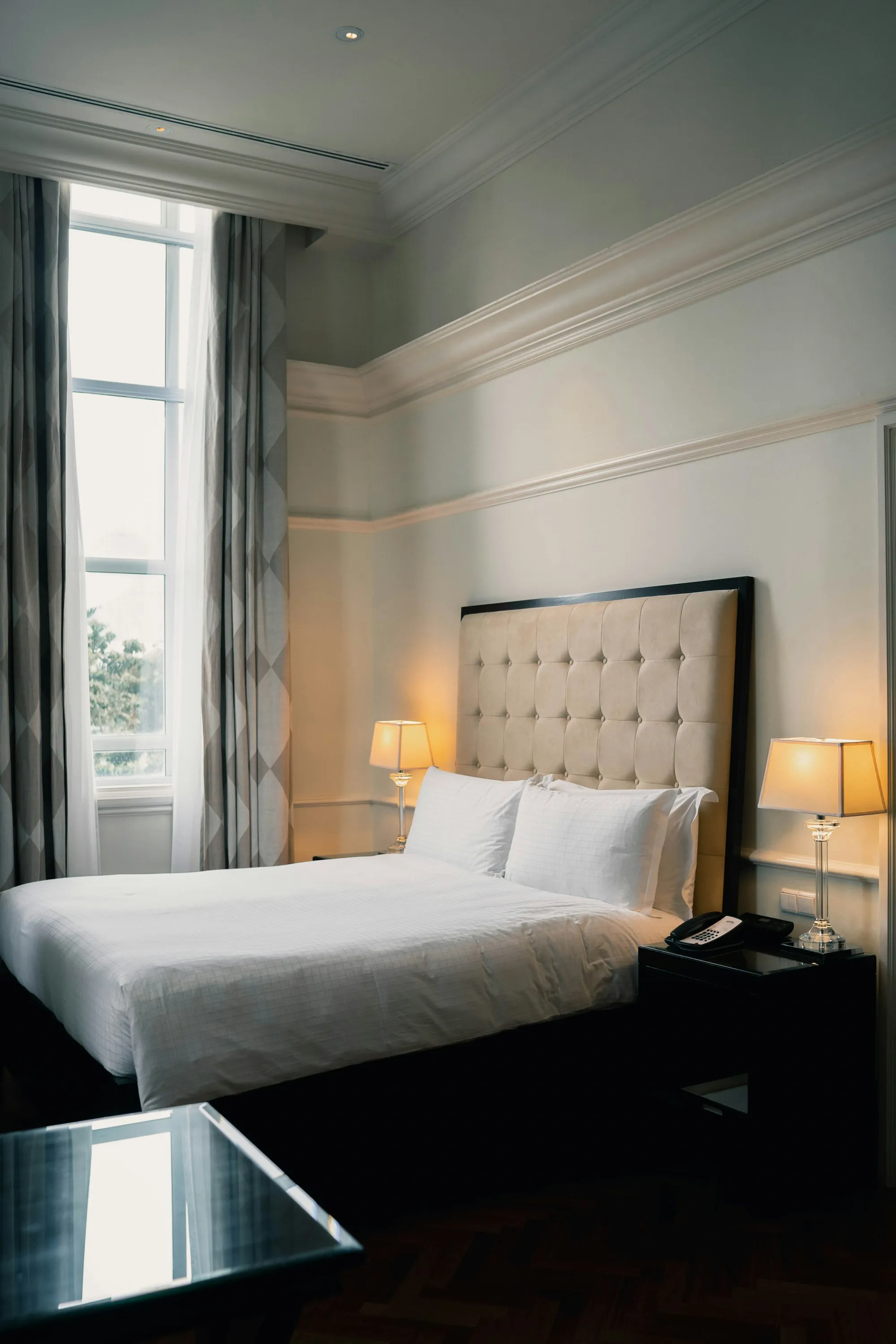 Hotel room with a made bed and warm bedside lamps
