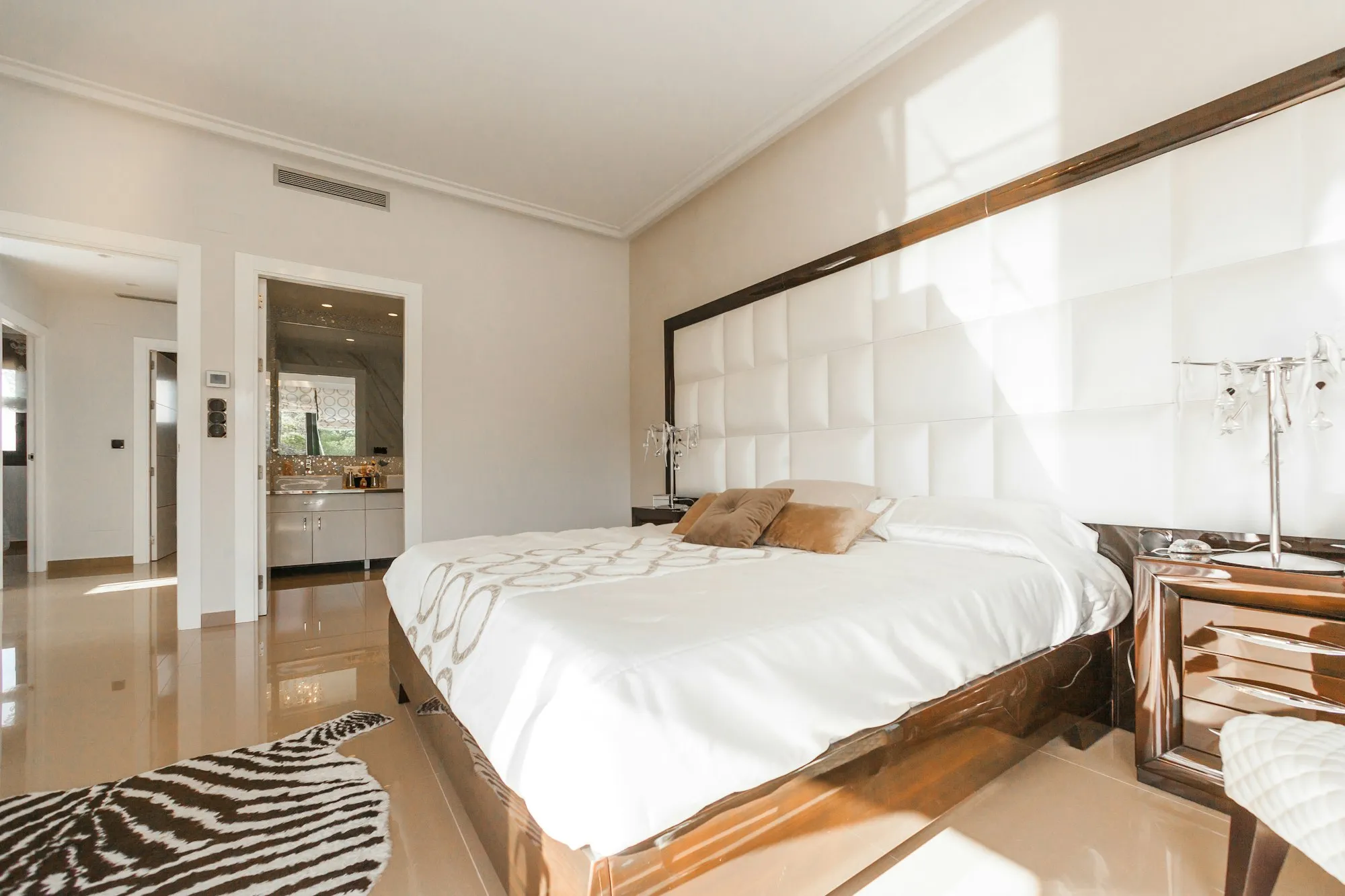 Spacious, sunlit hotel suite with a large white bed