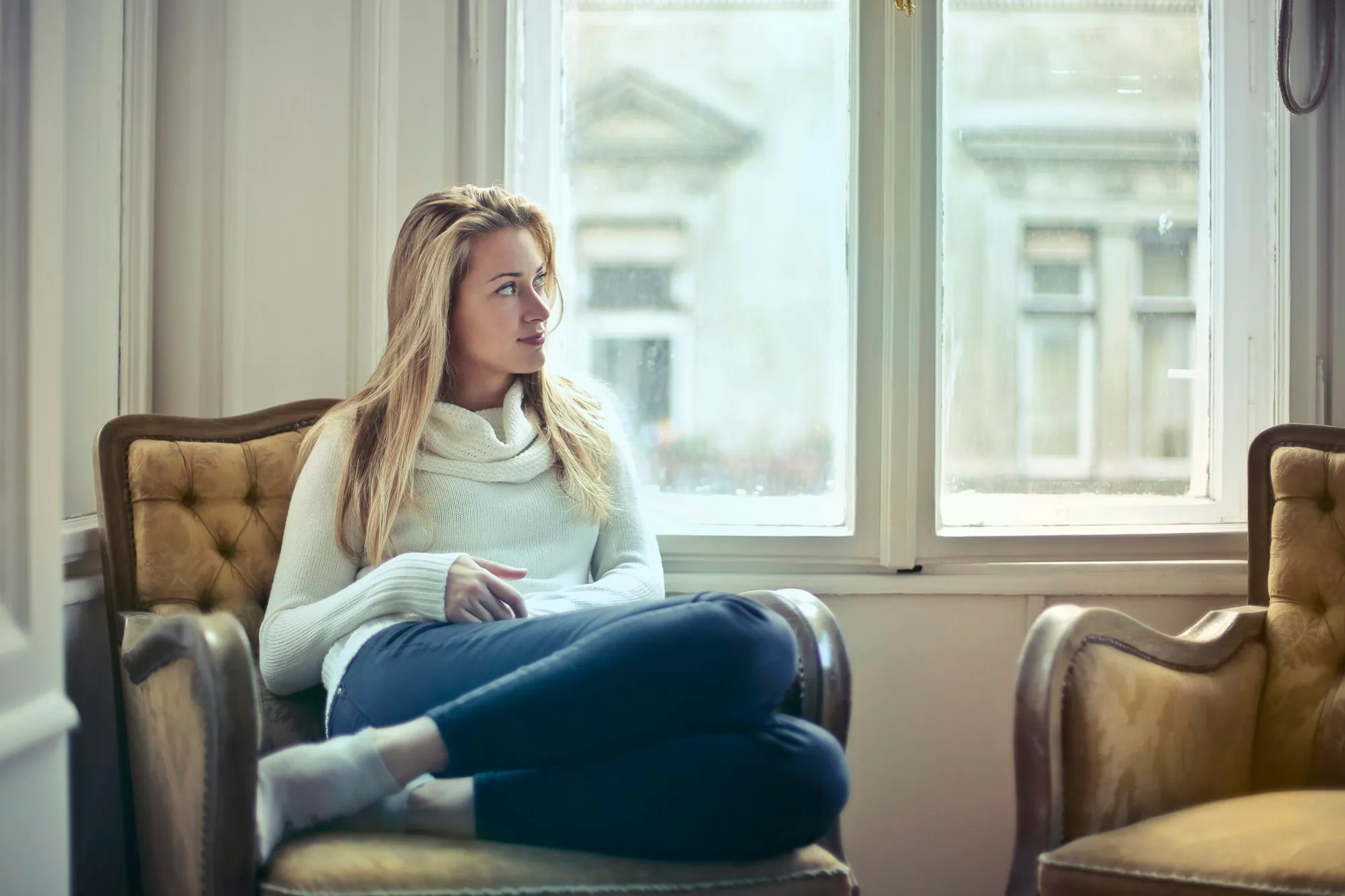 Woman relaxing in an armchair by a sunny window