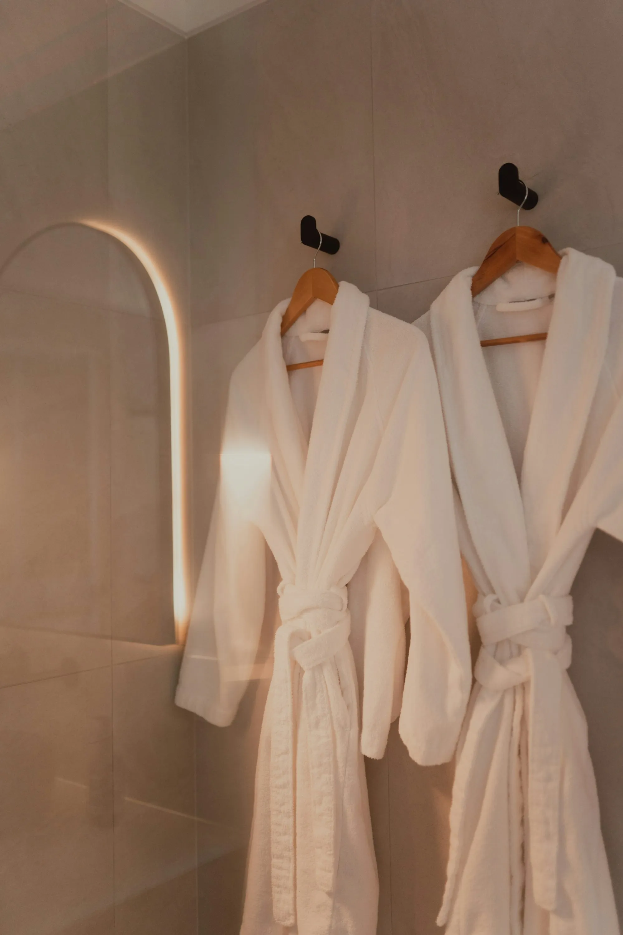 Two white robes hanging on hooks