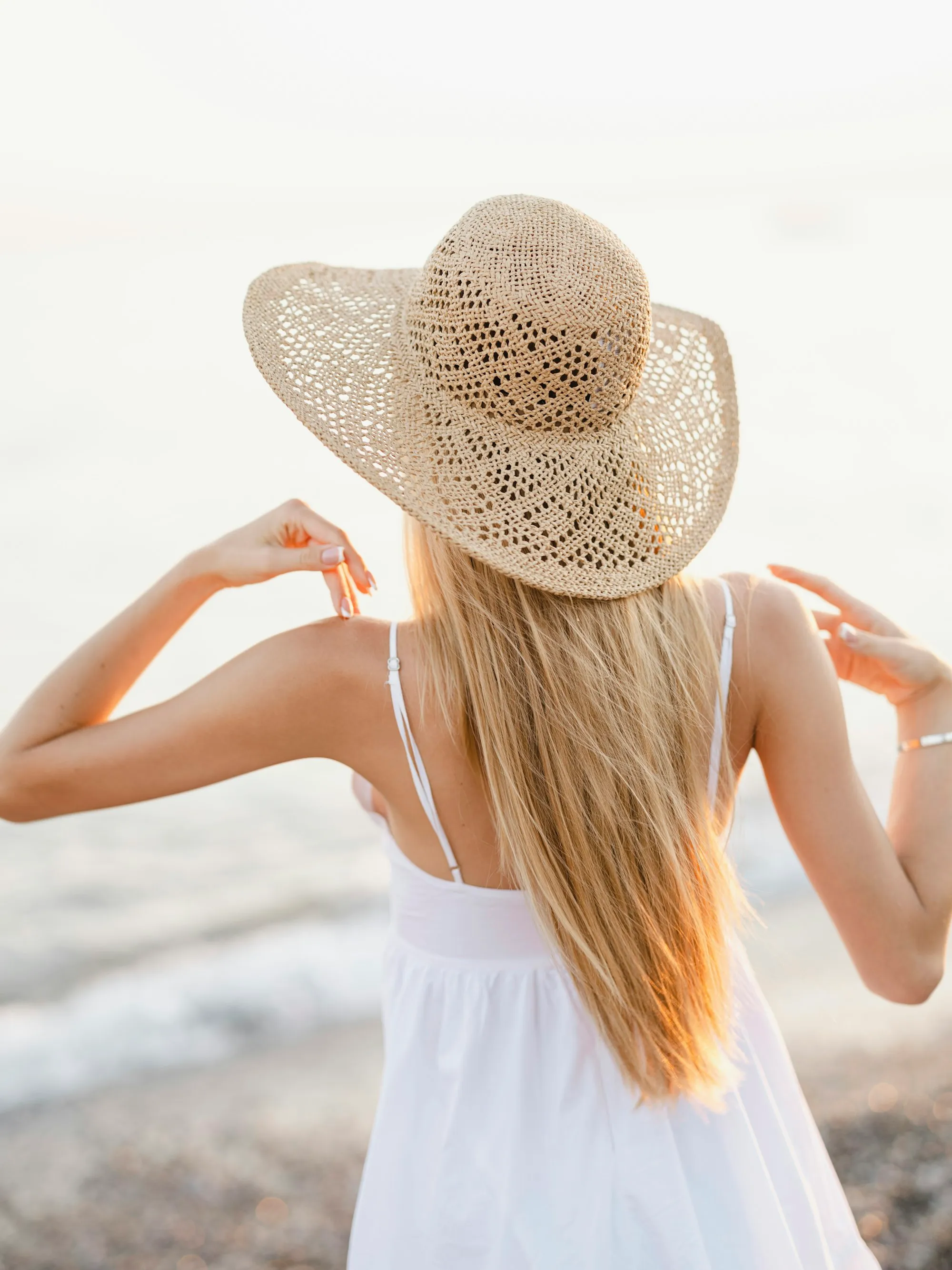 Woman in a straw sun hat and sundress in bright sunlight